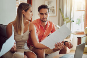 Unhappy, stressed and upset couple paying bills with a laptop