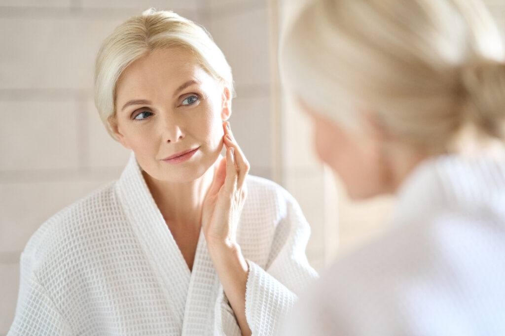 woman examining her skin in the mirror