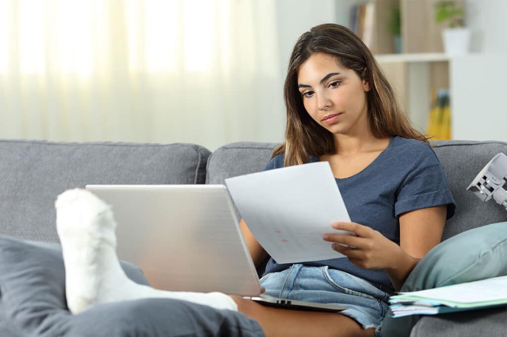 Woman with foot in cast, self employed working sitting on a couch in the living room at home