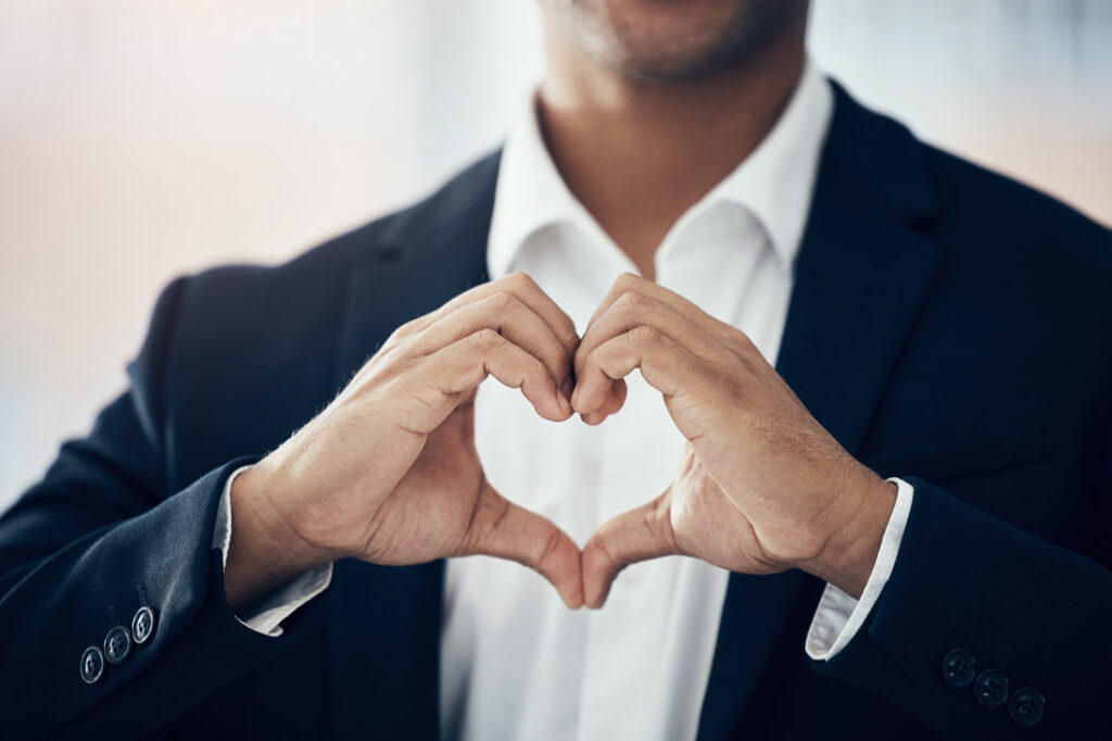 Business man hand heart gesture exemplifying small acts of kindness at work