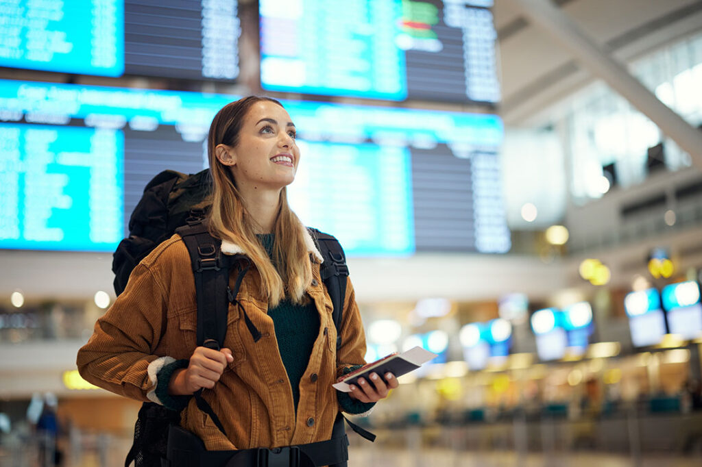 Excited woman with passport at airport with travel documents in hand