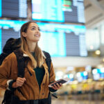 Excited woman with passport at airport with travel documents in hand