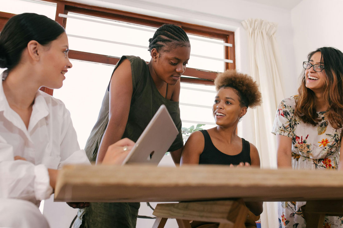 A group of diverse women of color having a meeting at a table