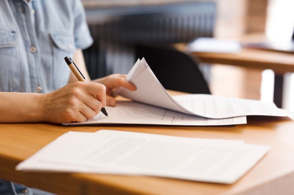 A close up image of a woman's hand as she signs a document.