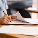 A close up image of a woman's hand as she signs a document.