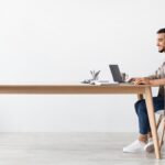 A freelancer works at the end of a long table.