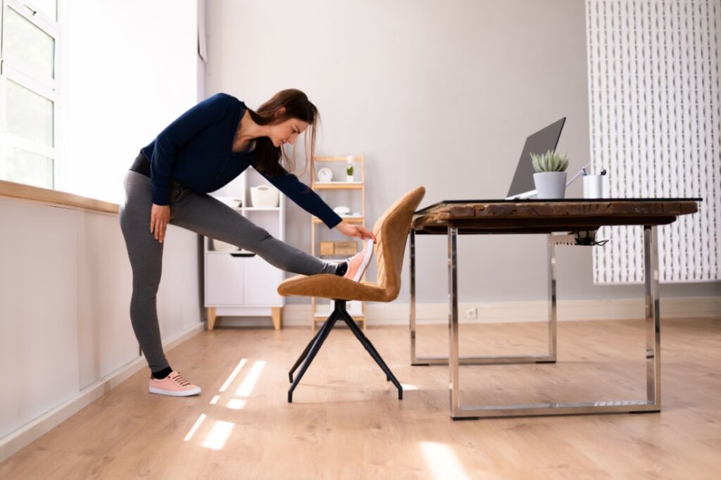 A woman stretches using her desk chair.