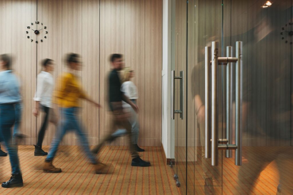 A timelapse photo of people entering and exiting a sleek office.