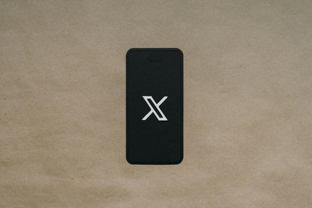 x logo on a mobile phone on a brown paper background