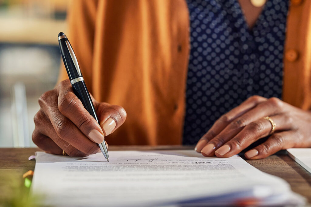 Close up of african american woman writing with pen on contract