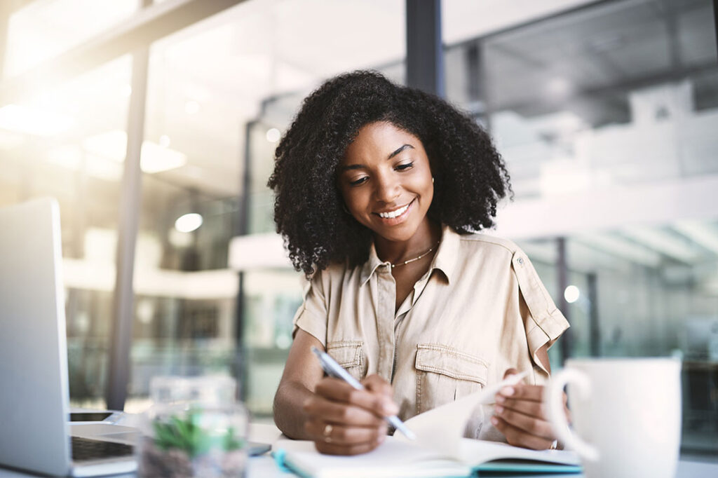 woman with notebook writing notes with pen in workplace