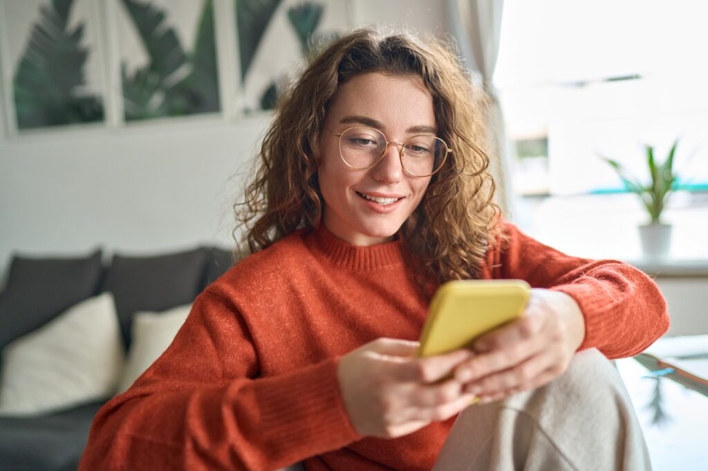 a woman looking at her phone while sitting on the couch