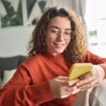 a woman looking at her phone while sitting on the couch