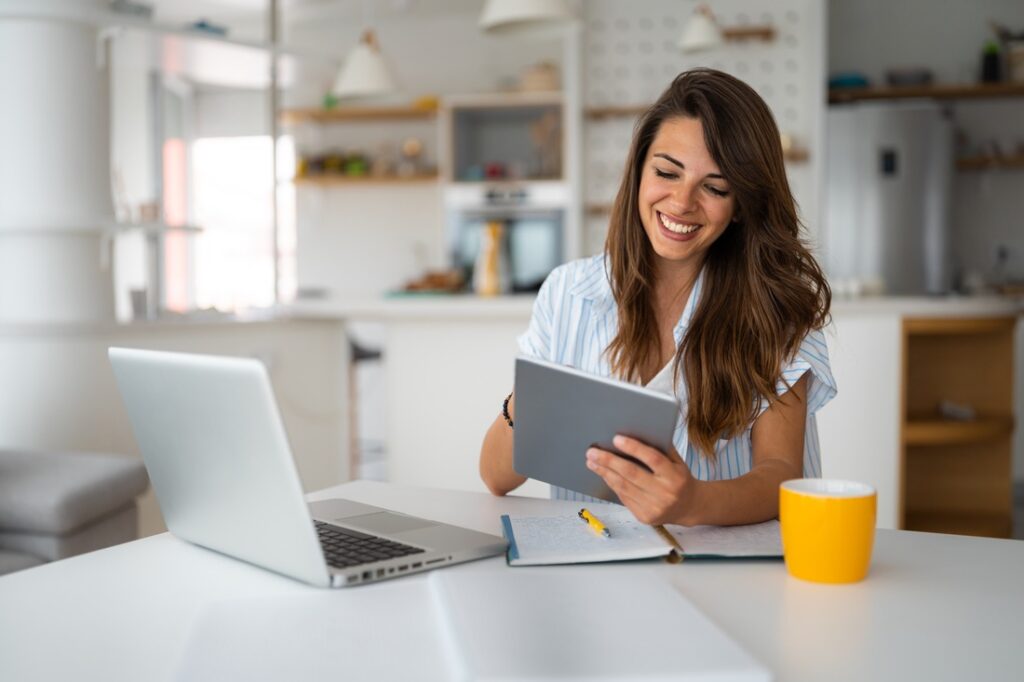 a woman sitting at a table using a tablet device