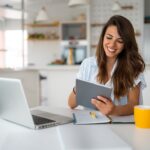 a woman sitting at a table using a tablet device