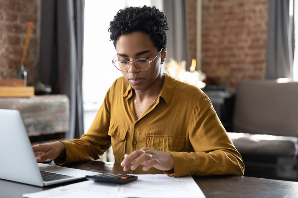 woman calculating finance and taxes with laptop computer at home workplace