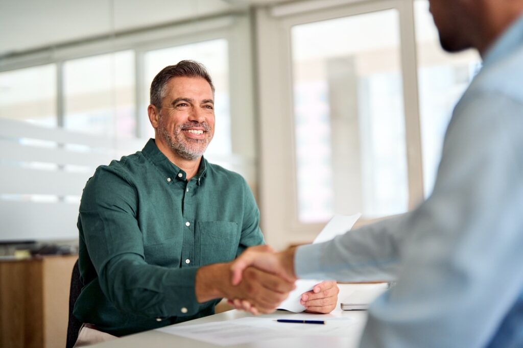 a man shaking another man's hand while both sit at a table