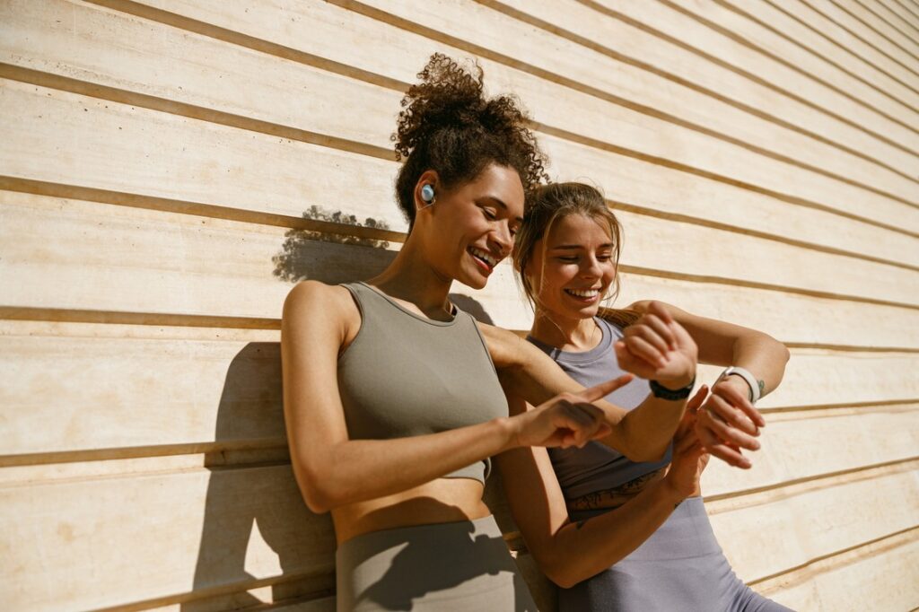 two women smiling while looking at their exercise watches