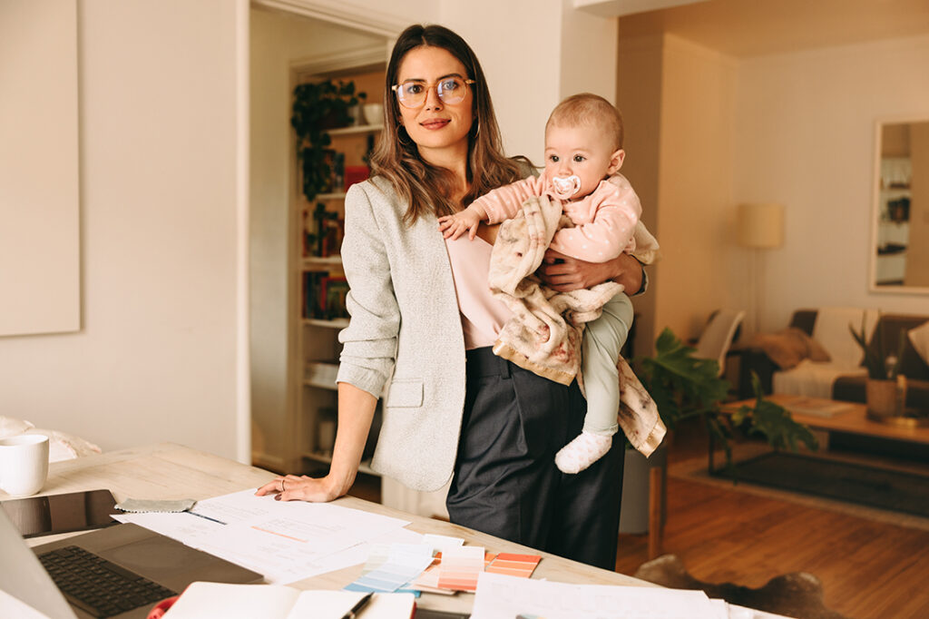 mother in business attire holding a baby