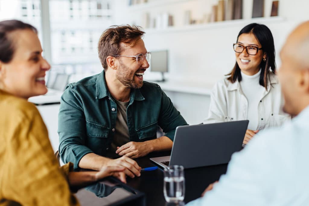 Group of happy business professionals sitting around a table and having a discussion