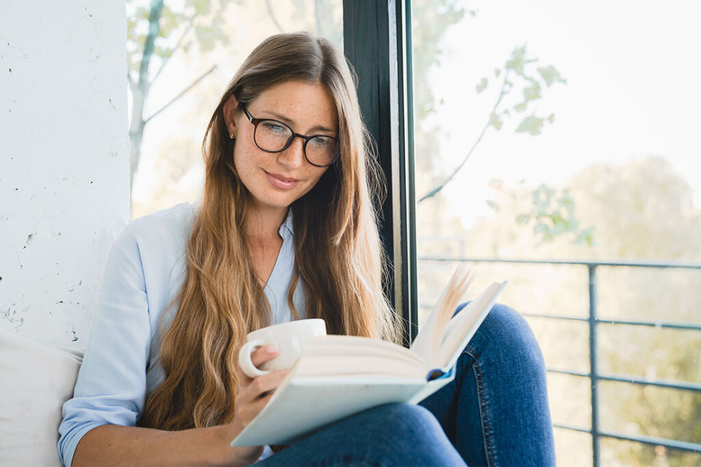 woman reading a book by the window