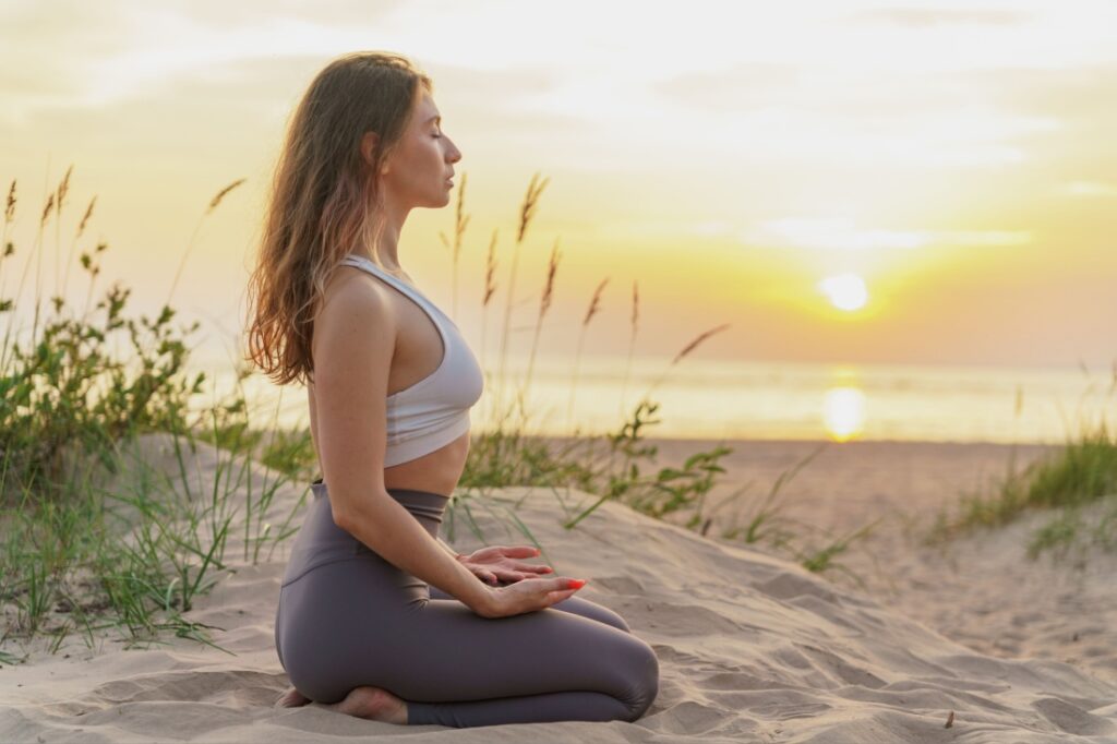 A woman practices yoga on the beach.