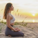 A woman practices yoga on the beach.