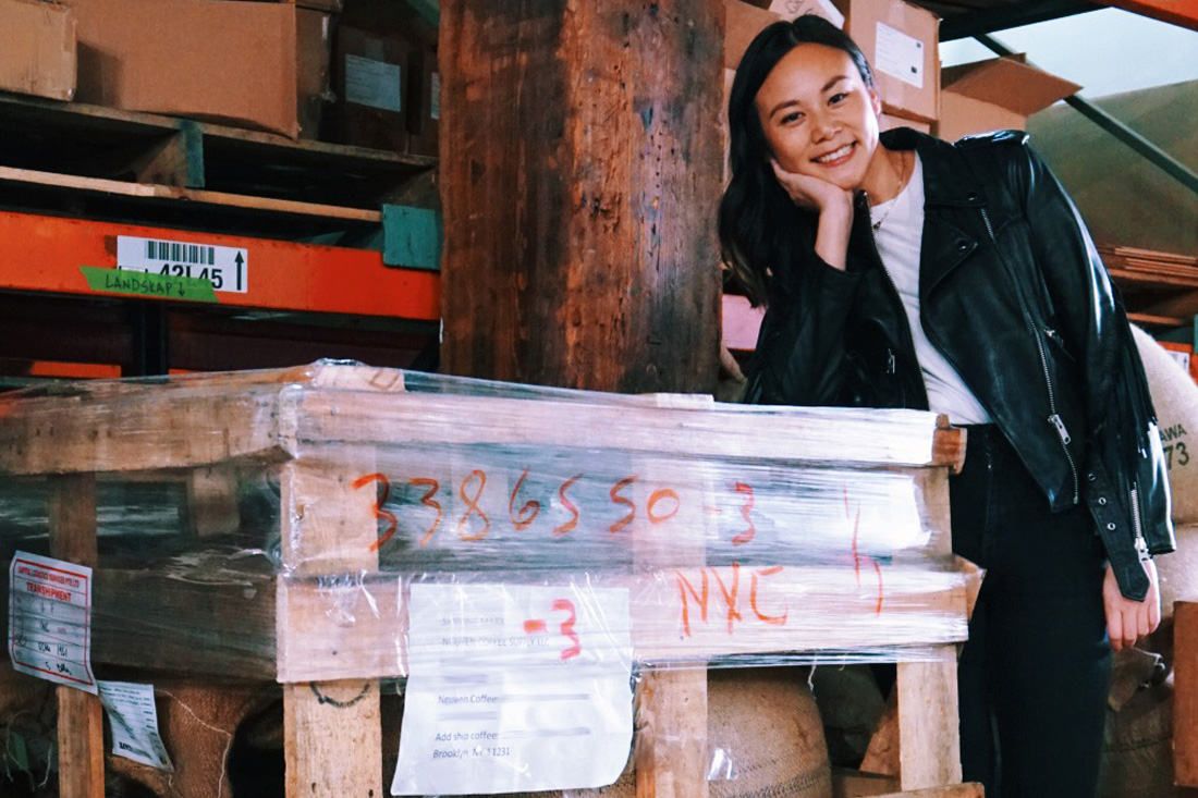 Sahra Nguyen poses next to a pallet in a warehouse.