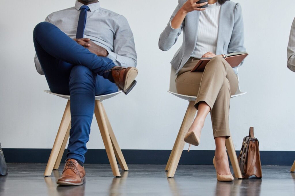 Close up of the different legs of people waiting in chairs for a job interview.