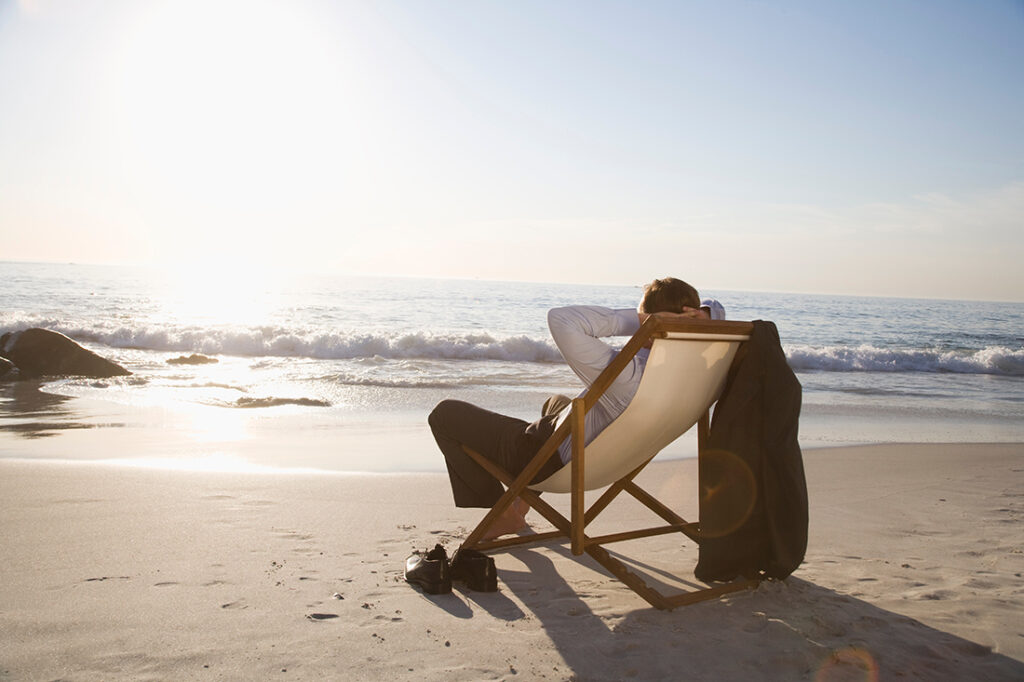 Business man sitting in a chair on the beach