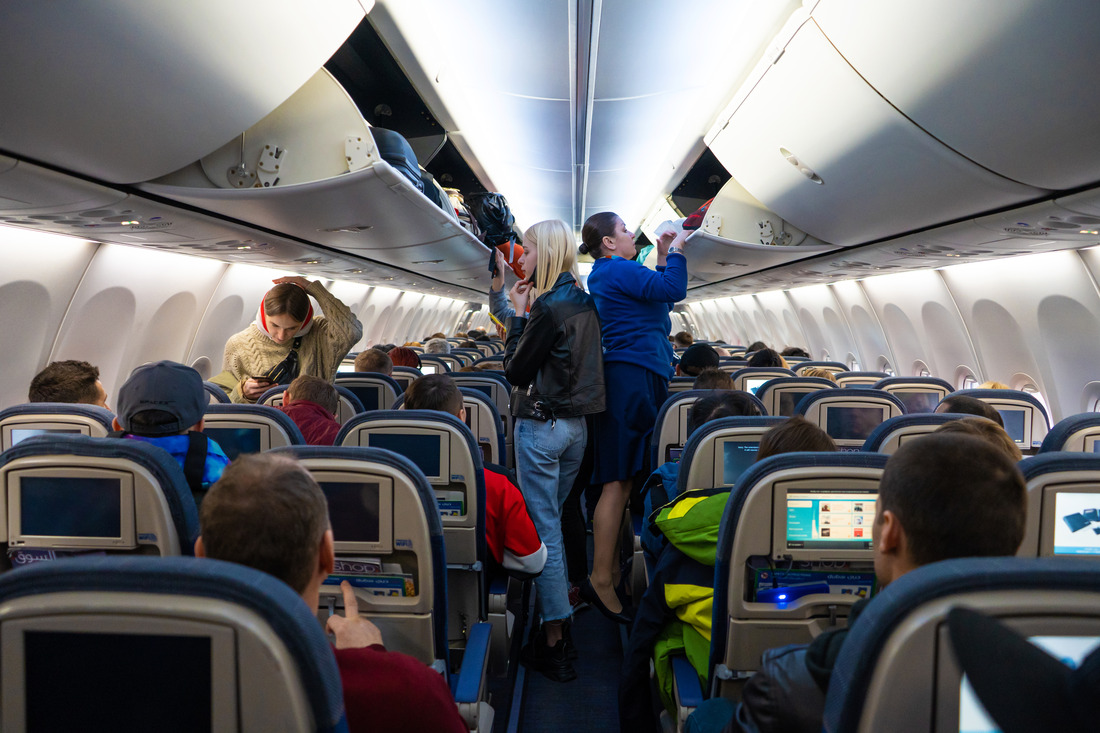 passengers sitting and standing in an airplane before it takes flight