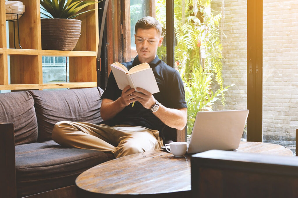 young man reading a book in cafe