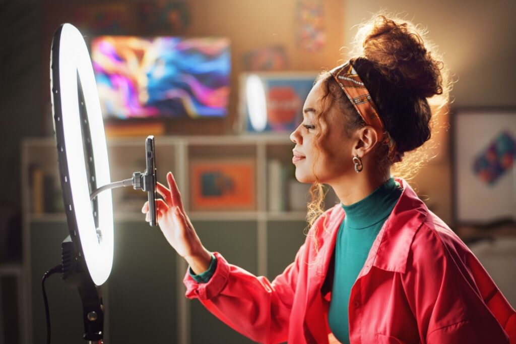 A woman sets her phone up in front of a ring light.