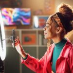 A woman sets her phone up in front of a ring light.