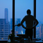 Businessman staring out office window at dark