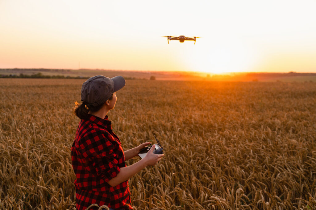 a woman farmer flying a drone over a wheat field