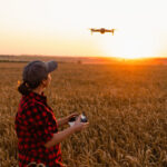 a woman farmer flying a drone over a wheat field