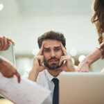 Business man with work crisis, people surrounding him handing documents