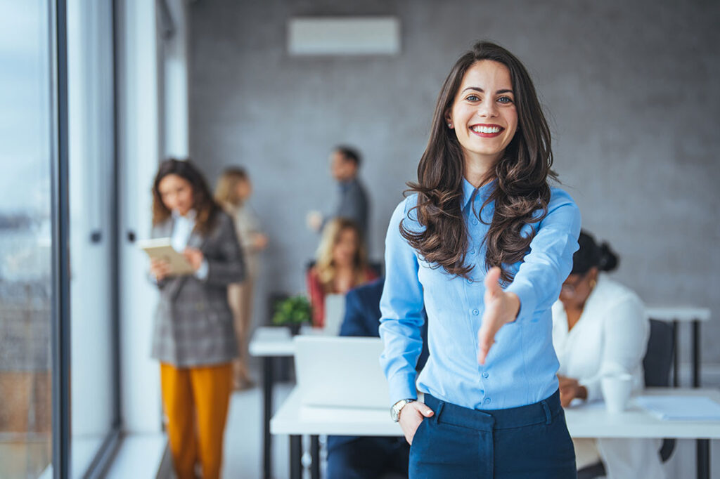 A happy office employee extends hand for a handshake