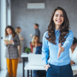 A happy office employee extends hand for a handshake