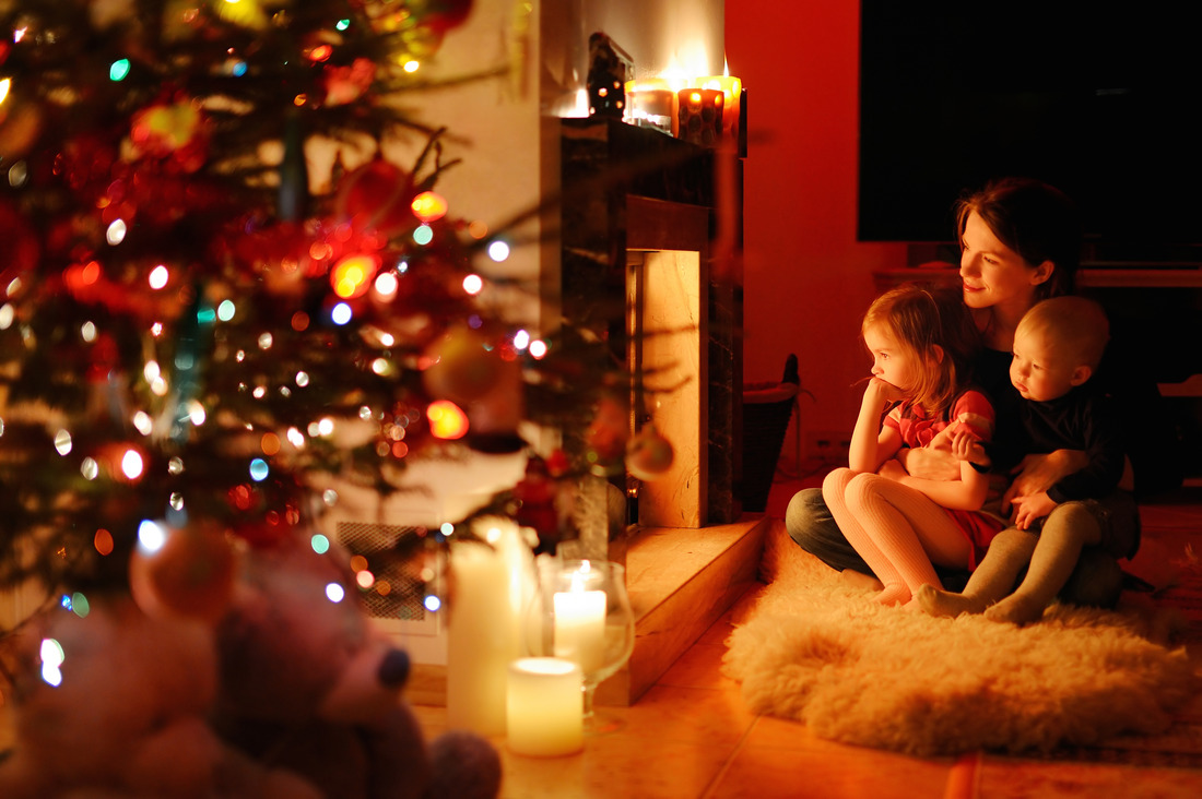 a mother and her two children sitting near a fireplace