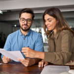 Smiling female reading document at business meeting reviewing paper