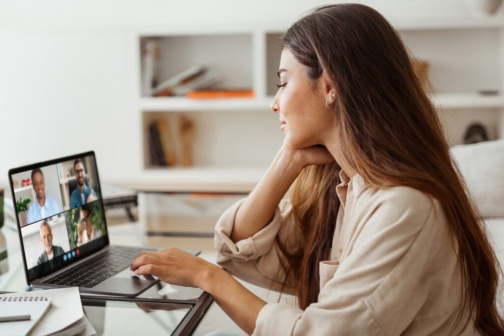 a woman sitting at a desk having a work video chat meeting on her laptop