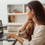 a woman sitting at a desk having a work video chat meeting on her laptop