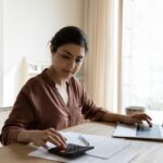 woman sitting at a desk doing paperwork and calculations