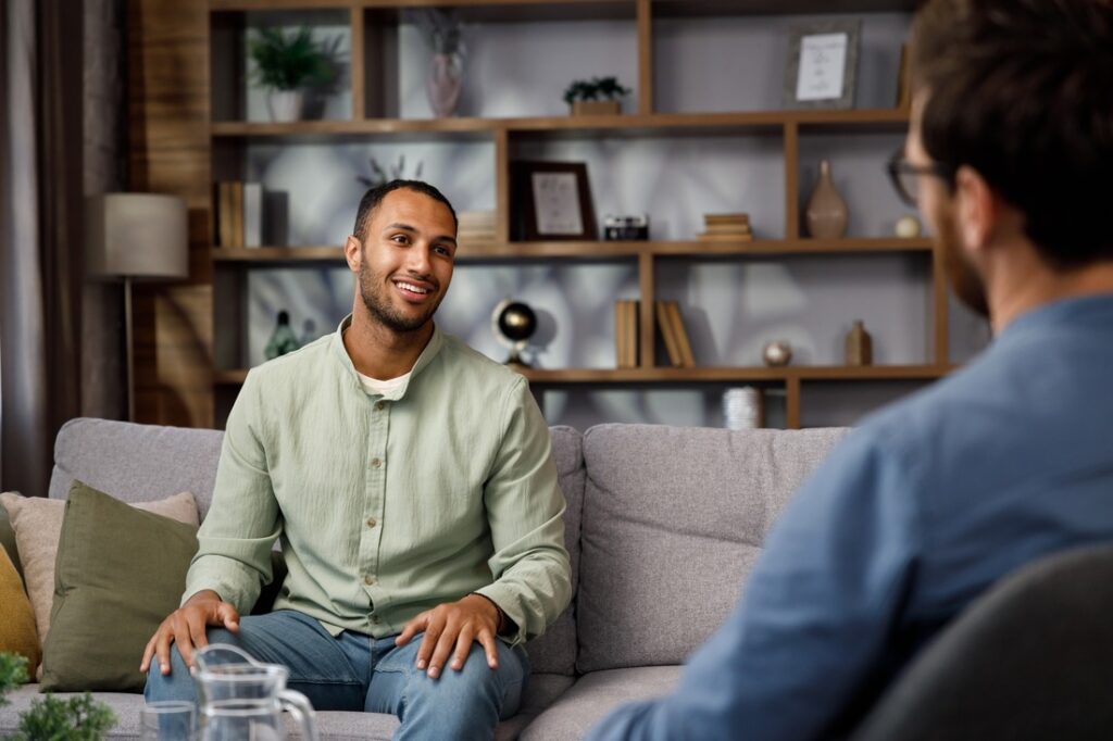 man sitting on a couch and speaking with a therapist