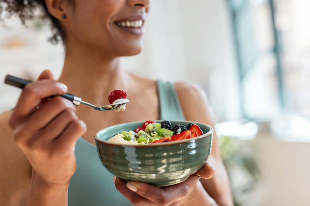 A woman eating a bowl of fruit