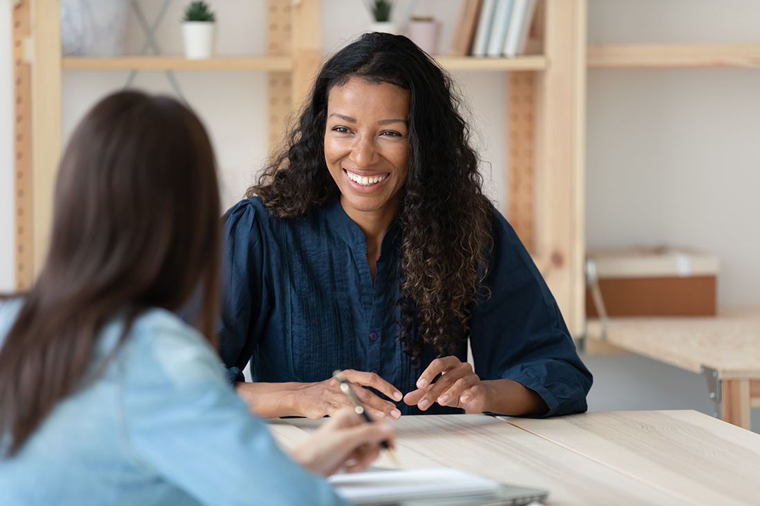 African American woman smiling and talking to colleague