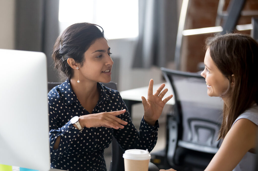 Two friendly female colleagues talking to each other