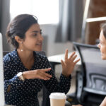 Two friendly female colleagues talking to each other